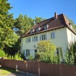 Das Bild zeigt die Straßenansicht des Bonhoeffer-Hauses in Berlin-Charlottenburg, eine klassische Fassade mit Vorgarten und Eingangstür. The picture shows the street view of the Bonhoeffer House in Berlin-Charlottenburg, featuring a classic façade with a front garden and entrance door.