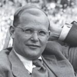 Das Bild zeigt Dietrich Bonhoeffer im Jahr 1939 in London, elegant gekleidet mit Anzug und Brille. The picture shows Dietrich Bonhoeffer in 1939 in London, dressed smartly in a suit and glasses.