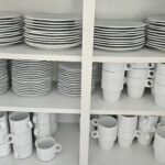 Das Bild zeigt einen Blick in ein Küchenschrank voller Tassen und Teller. The picture shows a cubbord full of cubs and plates.